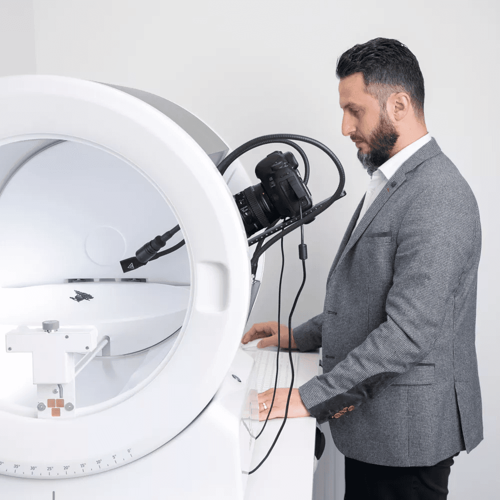Hombre con traje operando un dispositivo fotográfico Orbitvu